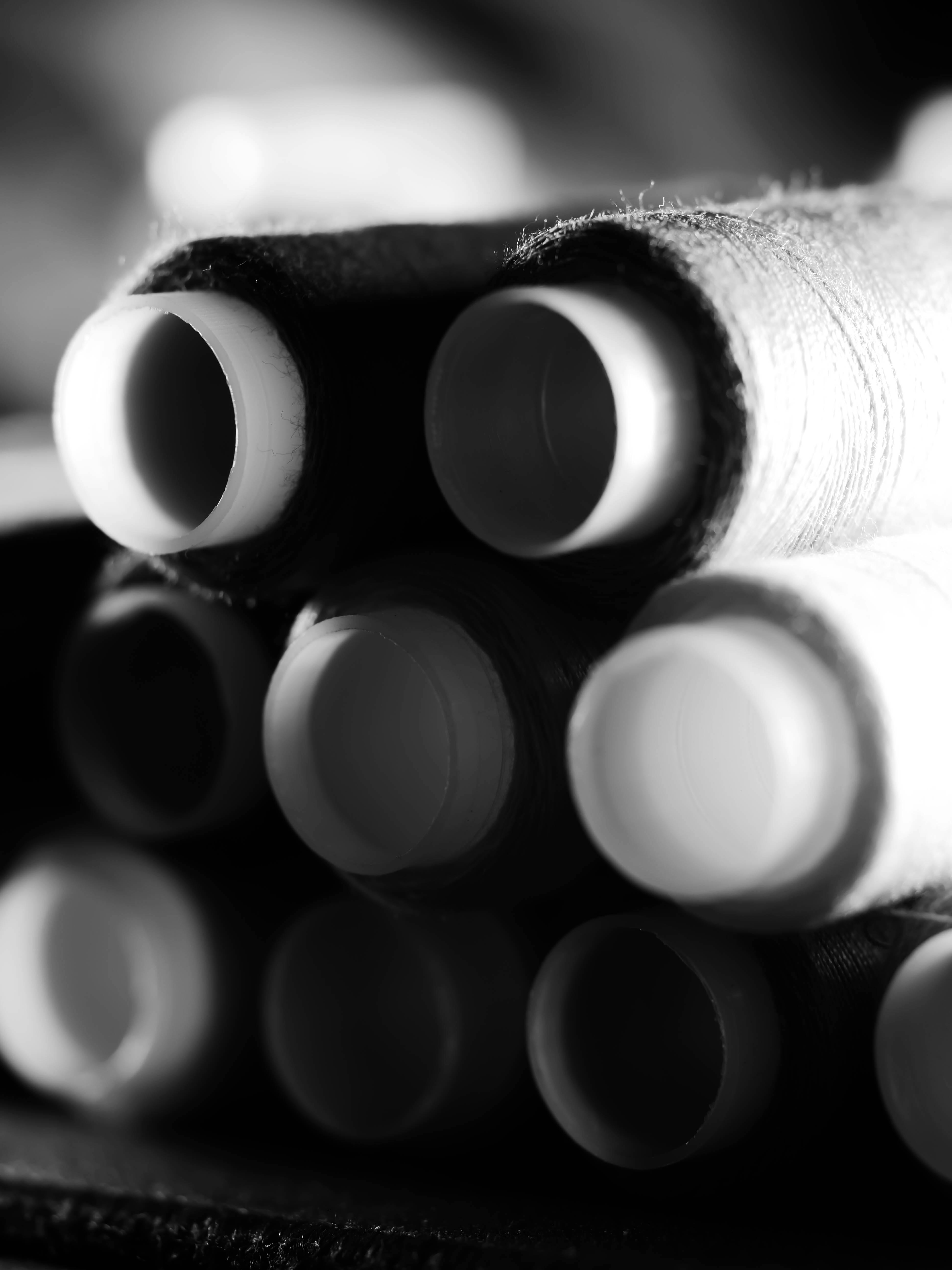 Black and white close-up image of stacked spools of thread creating a dramatic and artistic pattern.