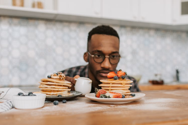 Man Wearing Eyeglasses Looking At Pancakes