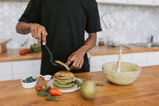 Person preparing delicious pancakes with fresh fruit in a stylish kitchen setting.