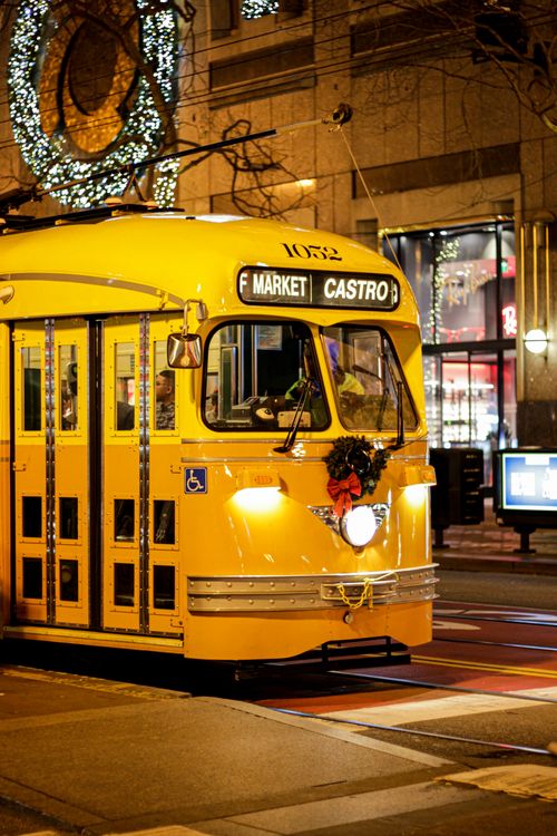 Free Vivid yellow tram adorned with festive decor, illuminated against a city's night backdrop. Stock Photo