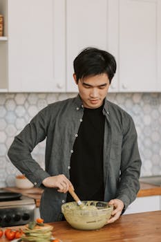 Young man mixing batter in a stylish kitchen setting, preparing breakfast.