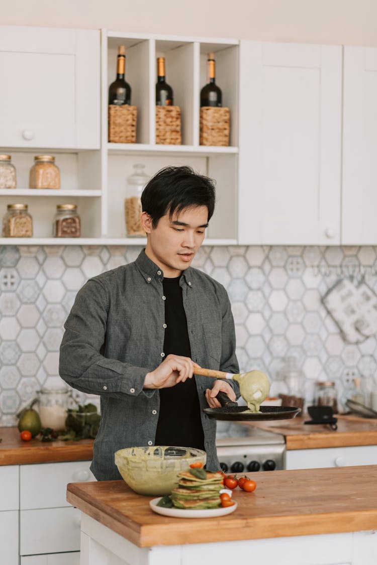 A Man Cooking Pancakes On A Kitchen