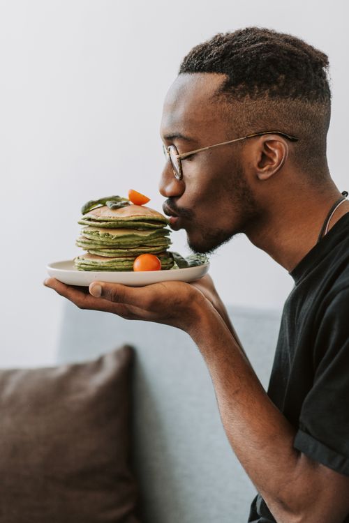 Free Adult man appreciating a stack of homemade pancakes with fresh cherry tomatoes. Stock Photo