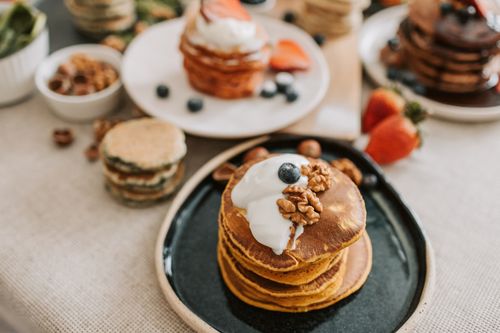 Free A stack of pancakes topped with yogurt, walnuts, and blueberries, perfect for a mouthwatering breakfast. Stock Photo