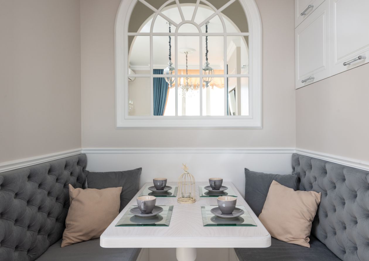 Breakfast nook with two tufted gray banquette benches and a small white table