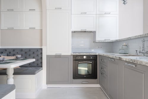 Served table with dishware placed near marble kitchen counter with white and gray cupboards and modern kitchenware in stylish apartment