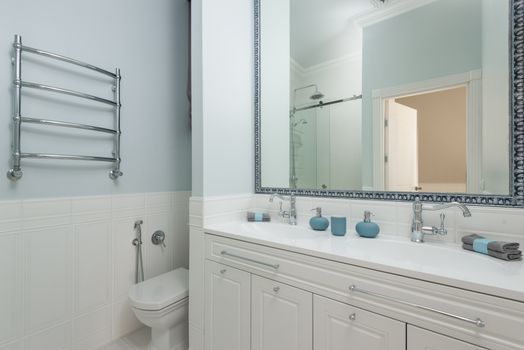 Contemporary bathroom with toilet bowl and cabinet with towels against washstands under mirror in hotel