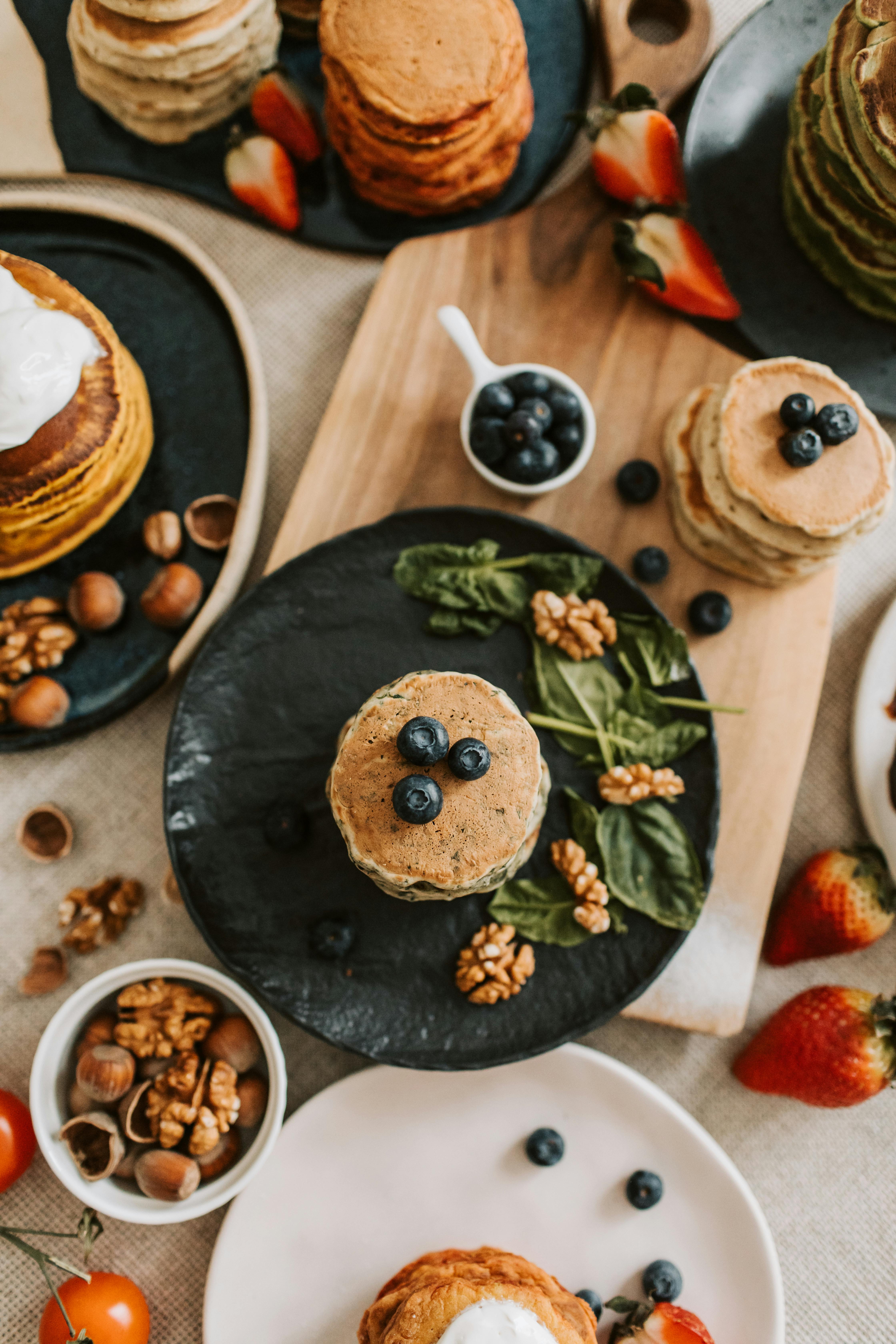 Mouthwatering breakfast pancakes topped with blueberries and accompaniments.