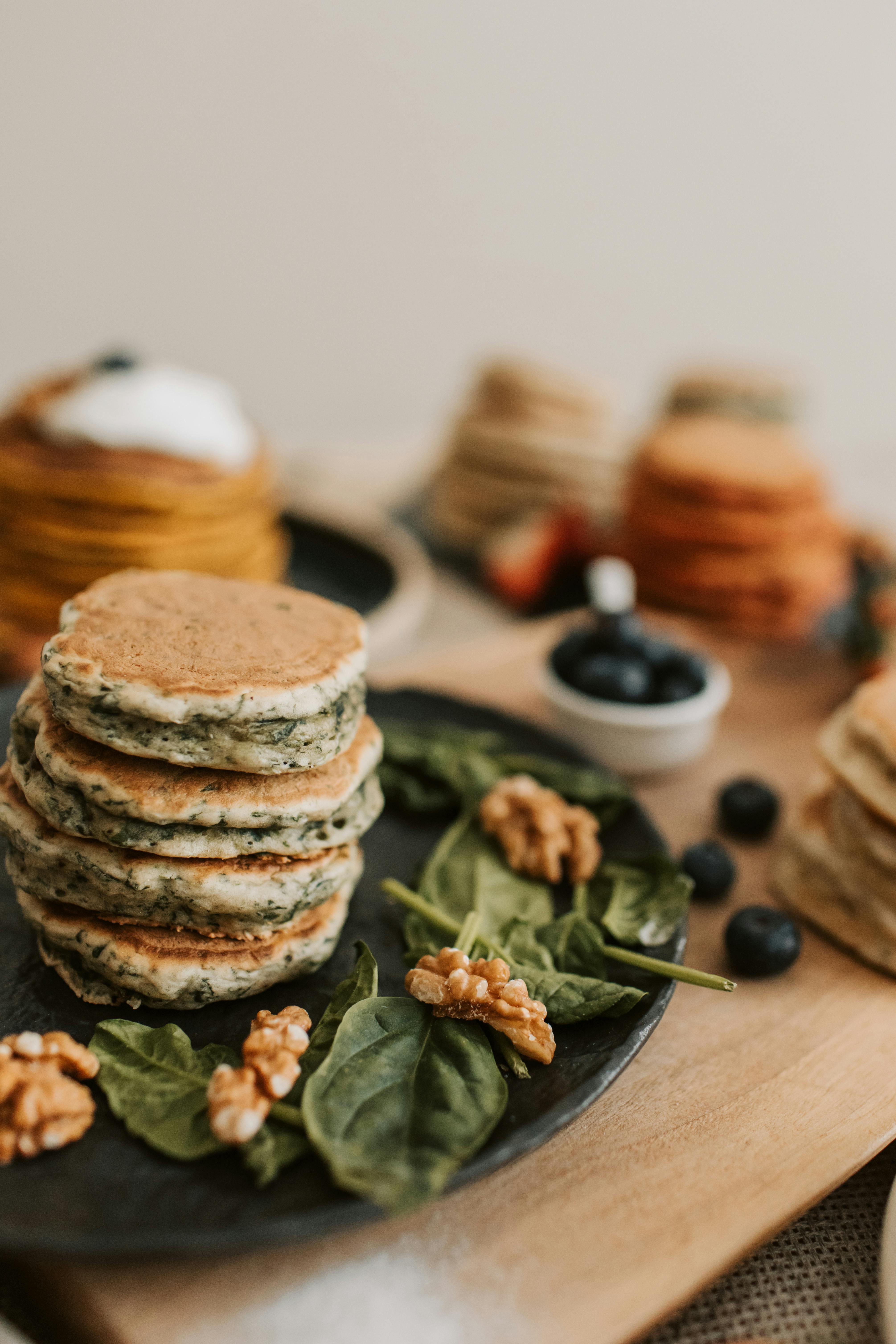 Appetizing pancakes served with fresh blueberries, walnuts, and spinach on a rustic plate.