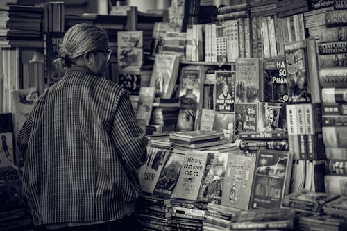 Pessoa Em Frente A Livros Diversos Em Fotografia Em Escala De Cinza