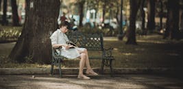 一位女士喜欢在宁静的公园长凳上读书