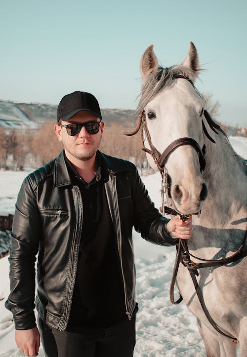 Man in Leather Jacket Holding the Lead of a Horse