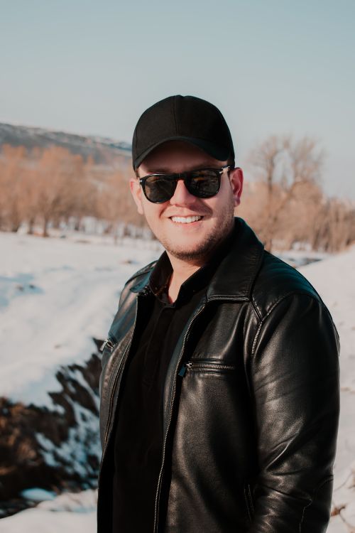 Free A cheerful man in sunglasses and leather jacket, enjoying a sunny winter day outdoors. Stock Photo