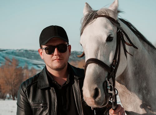 Man Standing Beside a White Horse