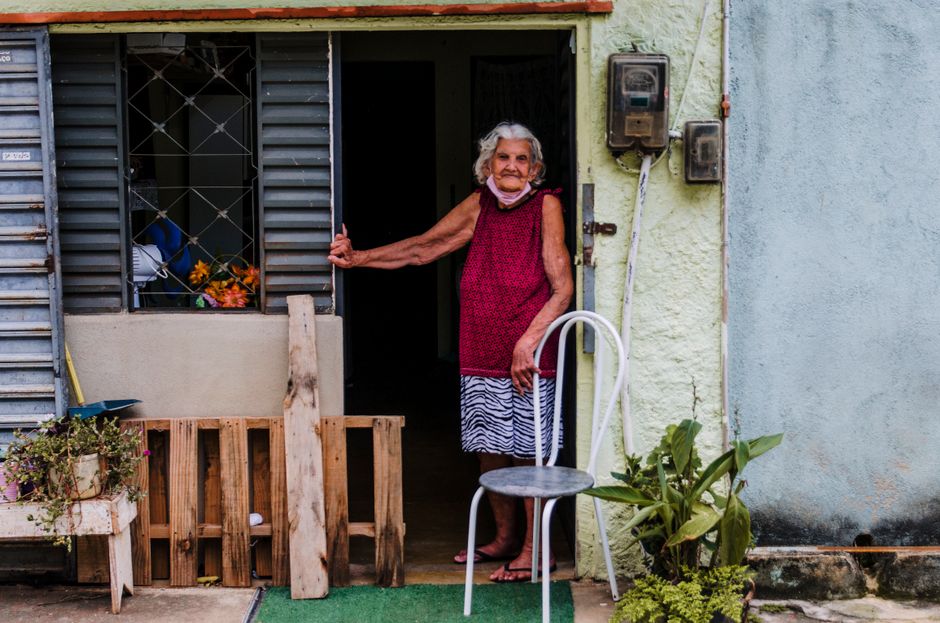A senior woman stands at her doorway, symbolizing resilience and home safety.