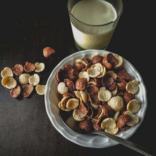Free Close-Up Shot of Cereals on a Breakfast Bowl beside a Glass of Milk Stock Photo
