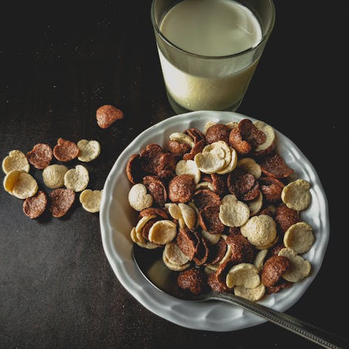 Close-Up Shot of Cereals on a Breakfast Bowl beside a Glass of Milk