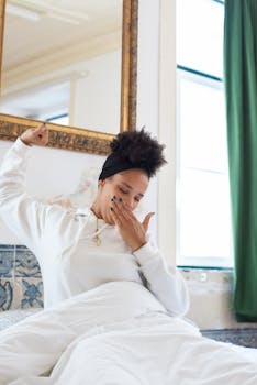 African American woman yawns in bed, enjoying a relaxed morning. Indoors setting.
