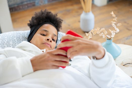 Woman lying on couch in white jacket using a smartphone, indoors setting.