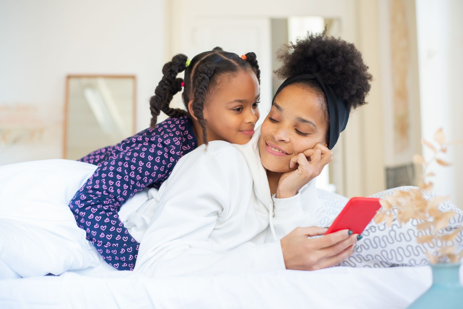 Monitor Your Kid's Phone Without Breaking Trust A heartwarming moment between a mother and daughter embracing while using a smartphone indoors