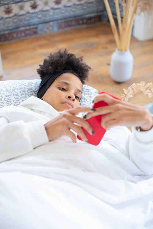 Woman Lying on Pillow While Using Cellphone