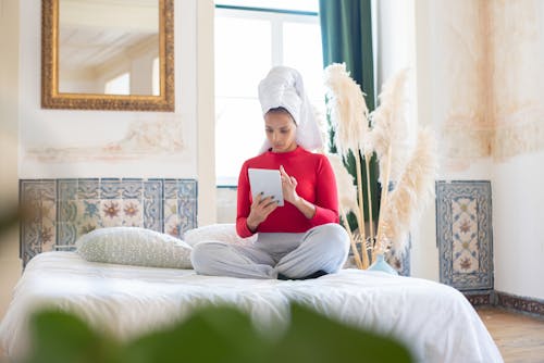 Free Woman With a Towel on Her Head Using a Tablet Stock Photo