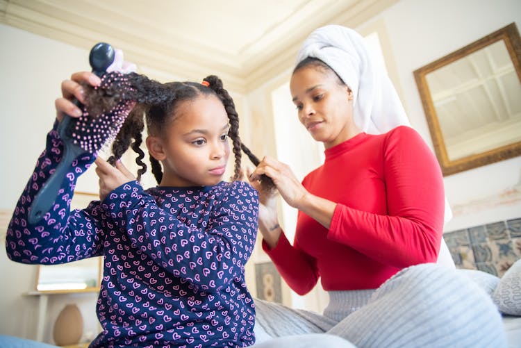 Woman Braiding The Hair Of A Girl