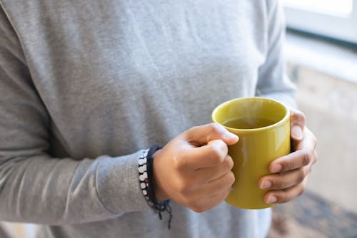 A Person Holding Hot Tea on a Mug