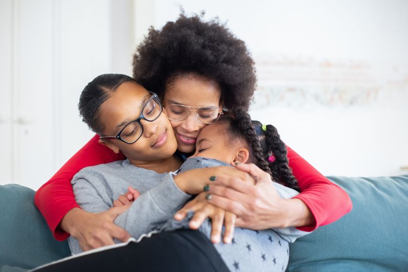 Heartwarming moment with family hugging and bonding on a comfortable couch indoors.