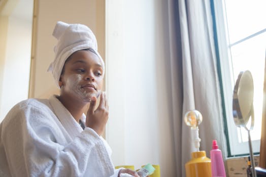 A woman in a bathrobe applying face cream, embodying a calm home spa skincare routine.
