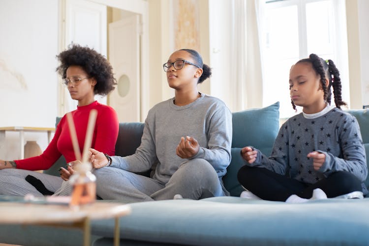 A Woman And Two Girls Meditating On A Couch