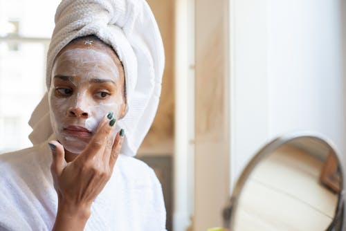 Free A Woman Applying Moisturizing Cream on her Face Stock Photo