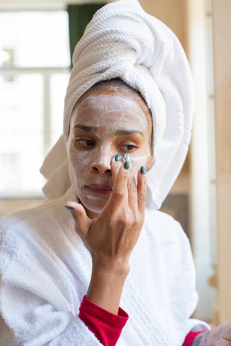 Woman Applying Cream On Her Face