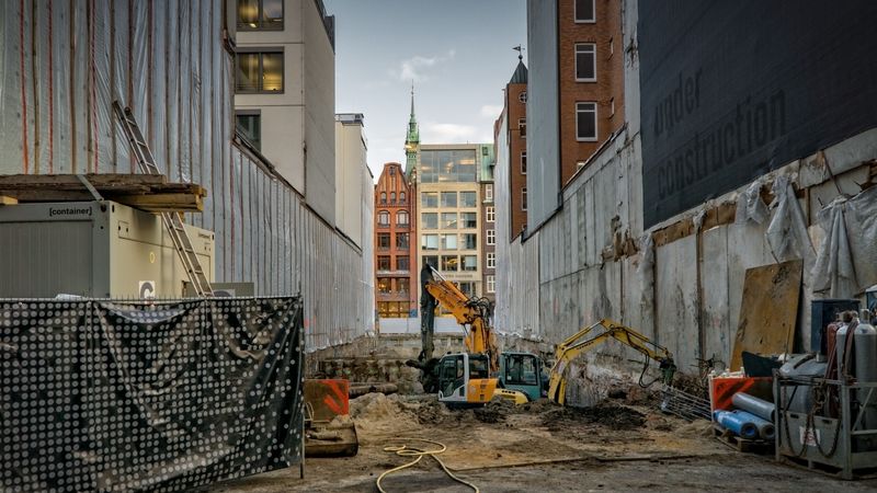Construction site in an urban area with excavators and scaffolding, showcasing development.