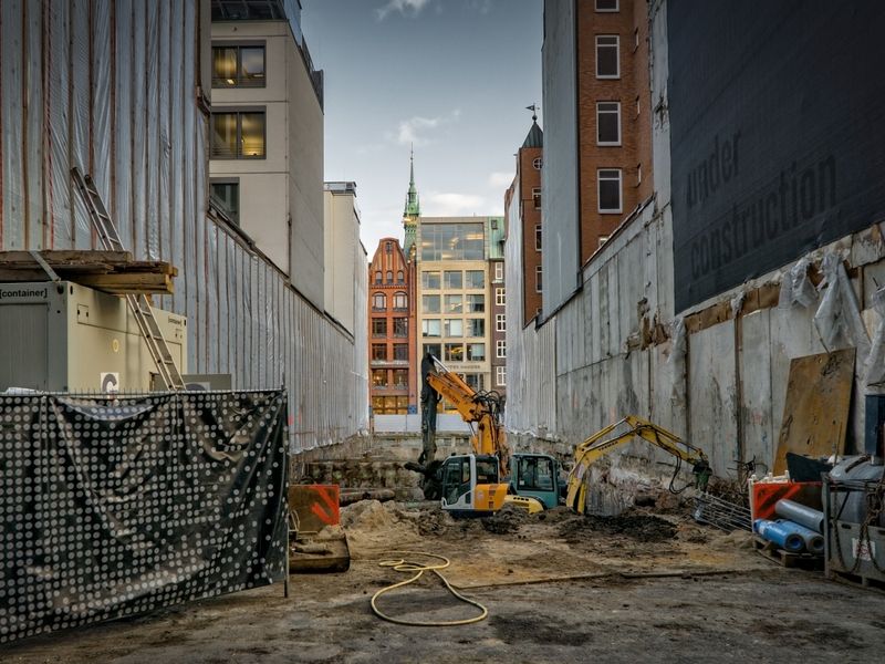 Urban construction site with excavator and hoarding