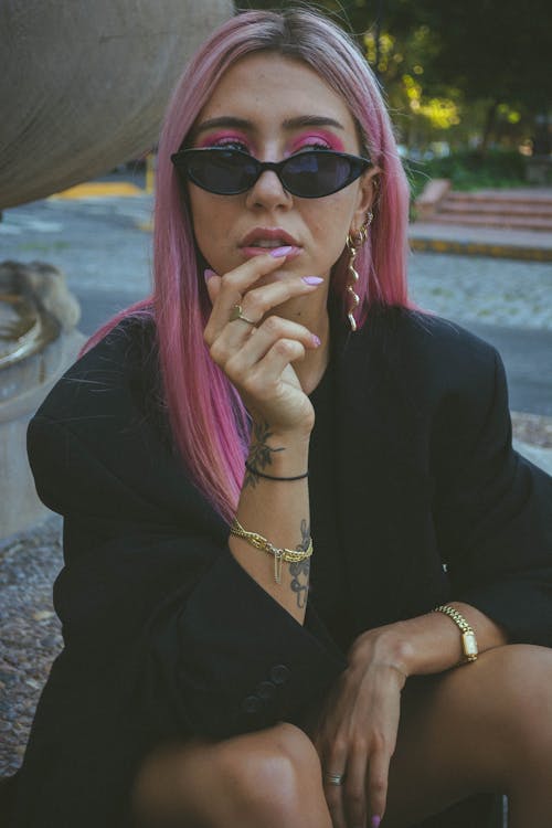 Photo of Woman in Black Coat and Sunglasses With Pink Colored Hair and Eye Makeup