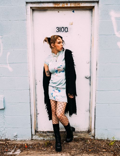 Fashionable young woman poses with attitude in urban setting, showcasing edgy style.