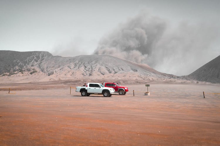 Pickup Trucks Parked Near A Smoking Volcano