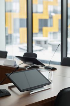 A sleek, modern office workspace with digital tablets and microphones on a conference table.