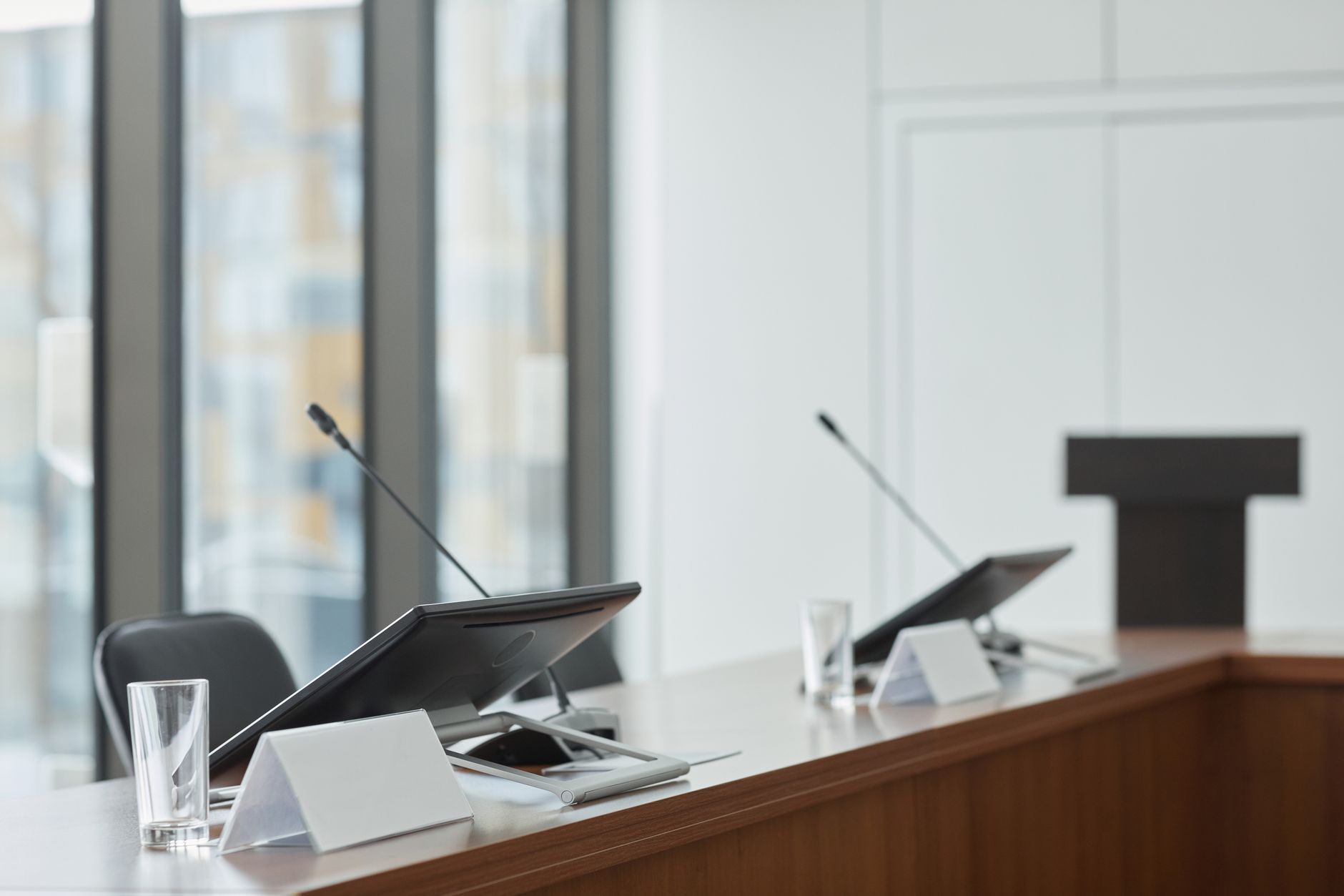 Empty boardroom with microphones, monitors, and clear windows creating a professional setting.