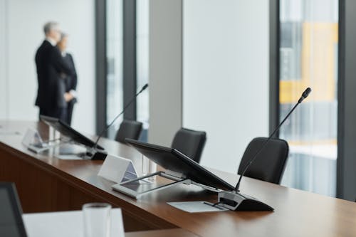 Monitors and Microphone on a Wooden Conference Table 
