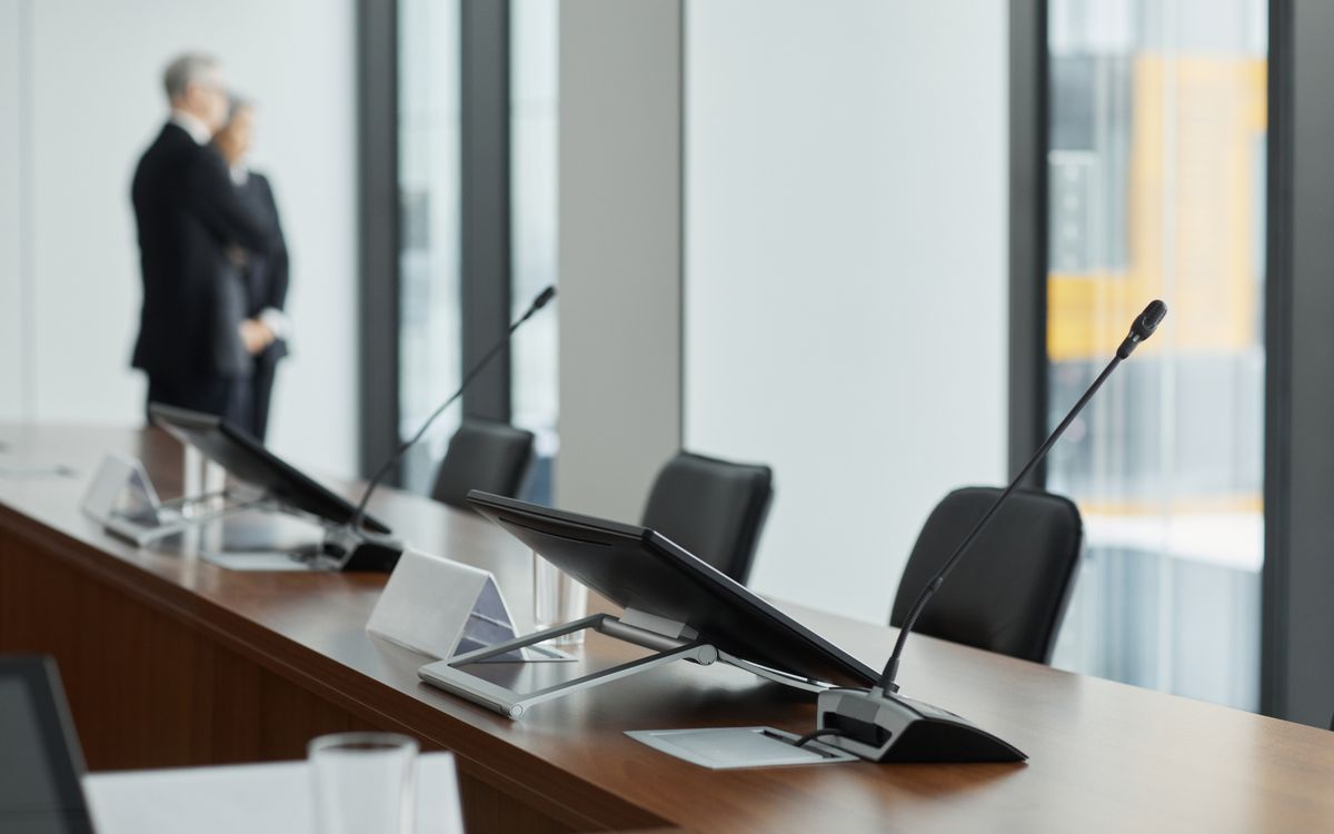 Sleek conference room setup with microphones, digital displays, and modern design elements.