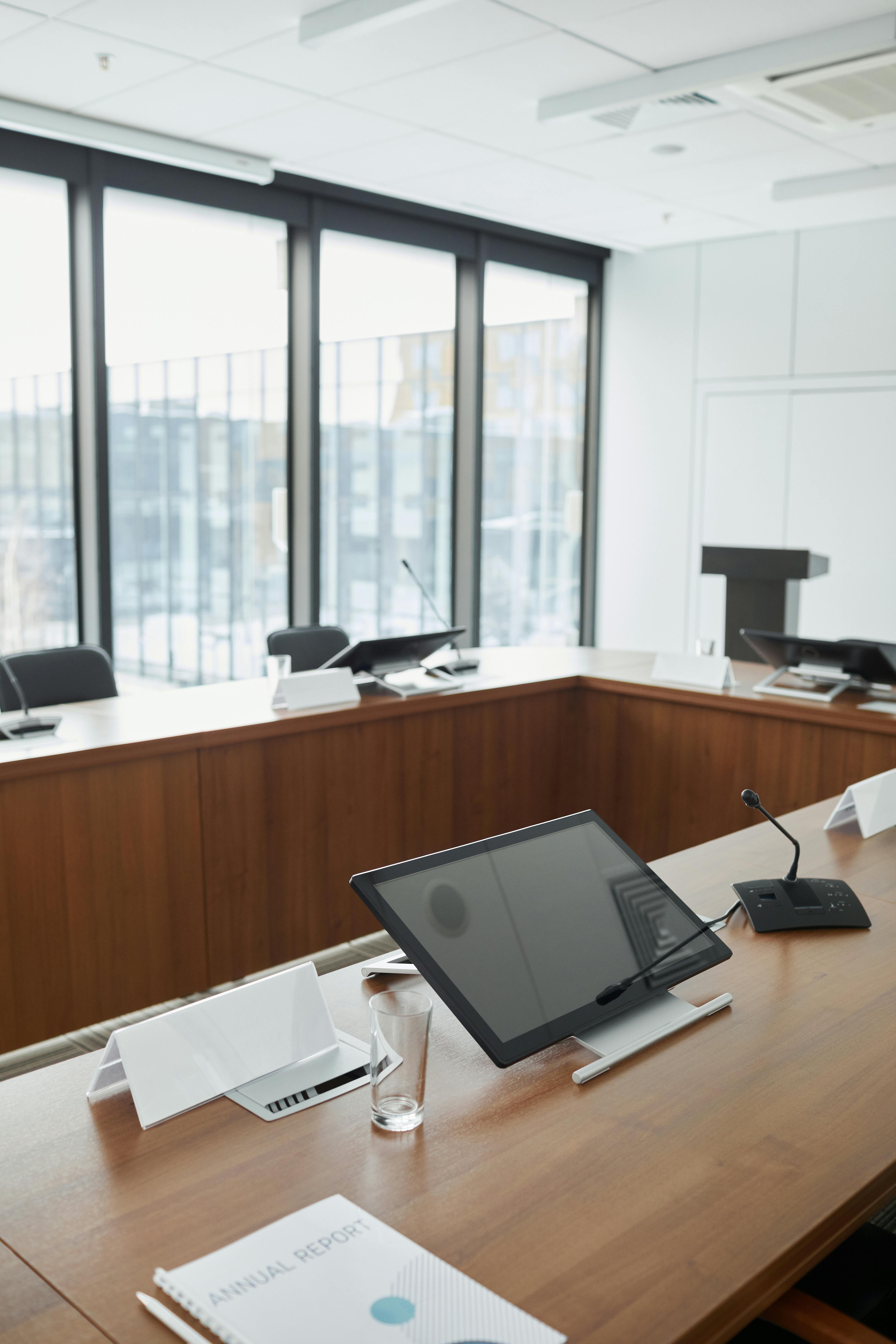 Spacious conference room equipped with digital screens and microphones, ideal for meetings.