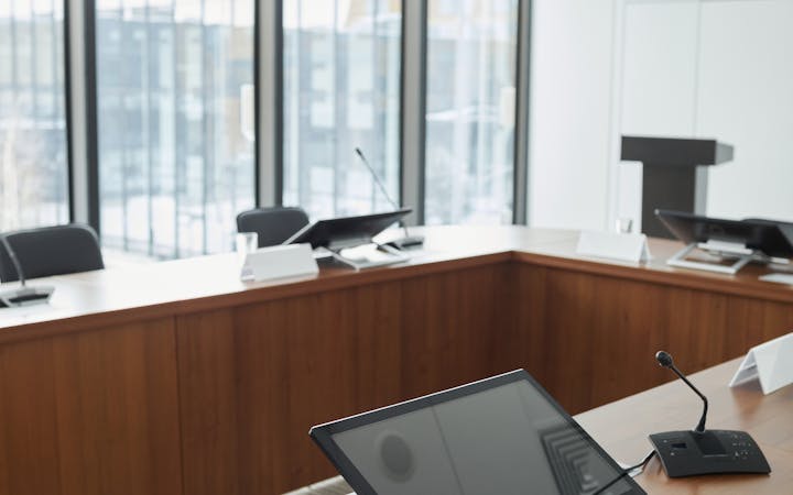 Spacious conference room equipped with digital screens and microphones, ideal for meetings.