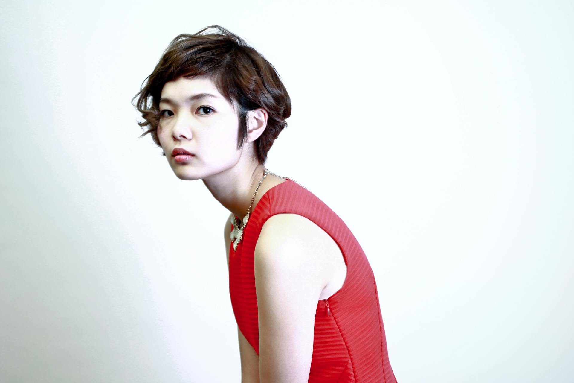 Elegant portrait showcasing a young woman with short hair in a vibrant red dress, exuding modern fashion.