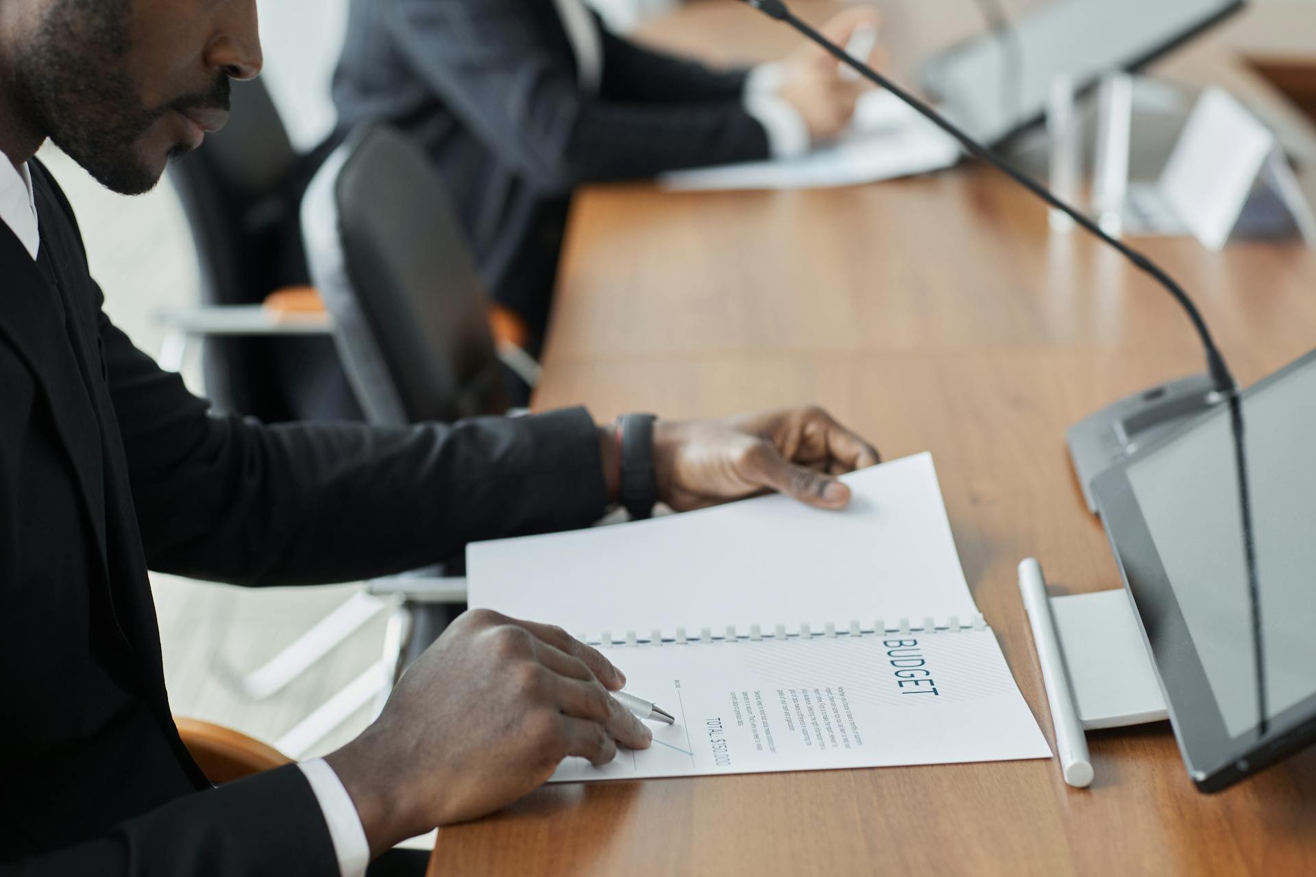 Professional businessman examining budget documents during an office meeting, showcasing focus and analysis.