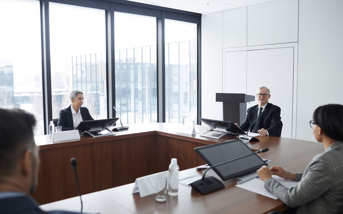 Business professionals in a board meeting in a modern conference room, engaging in discussion.