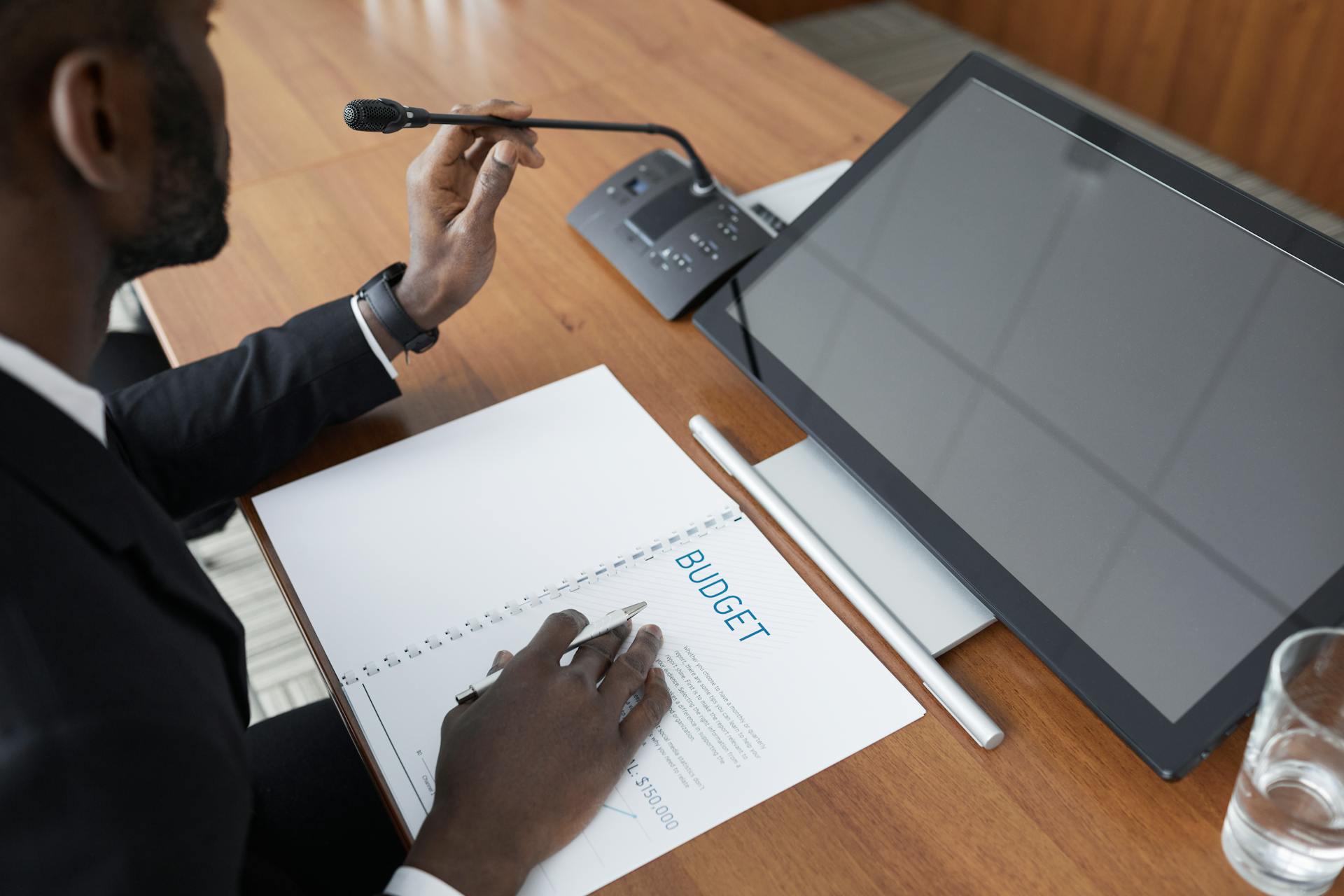 African American man in a meeting reviewing a budget document with a microphone