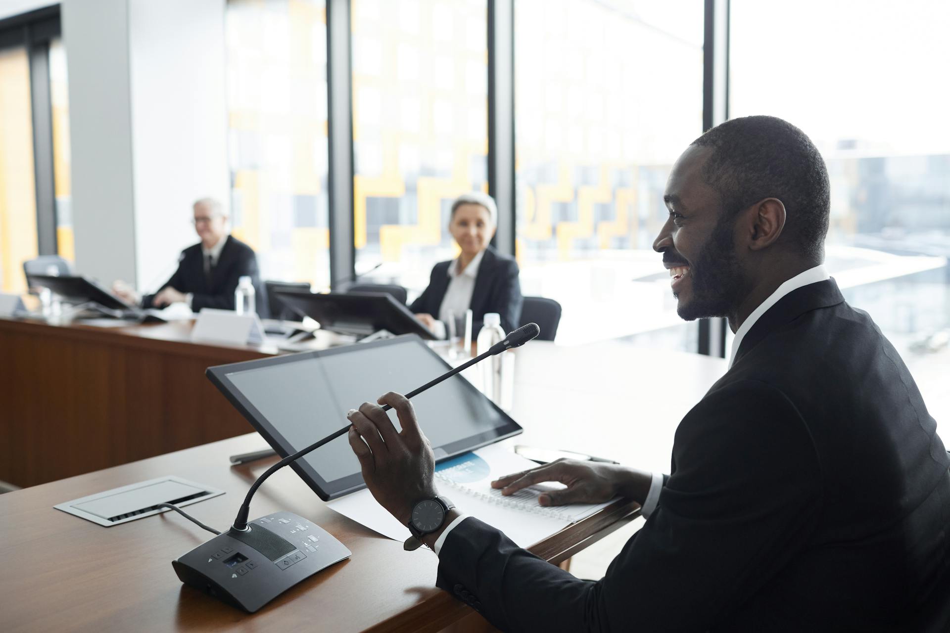 Professional business meeting with smiling participants discussing strategies at a conference table.