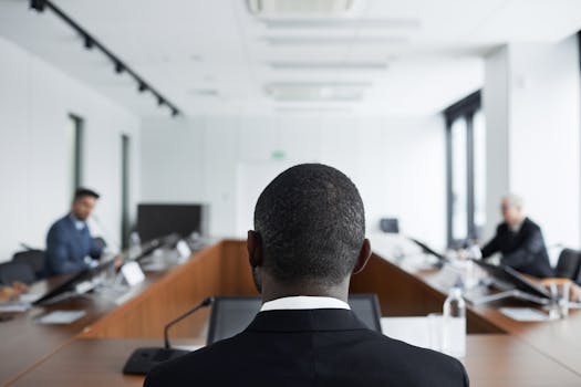 Back view of professionals in a business meeting in a bright conference room.